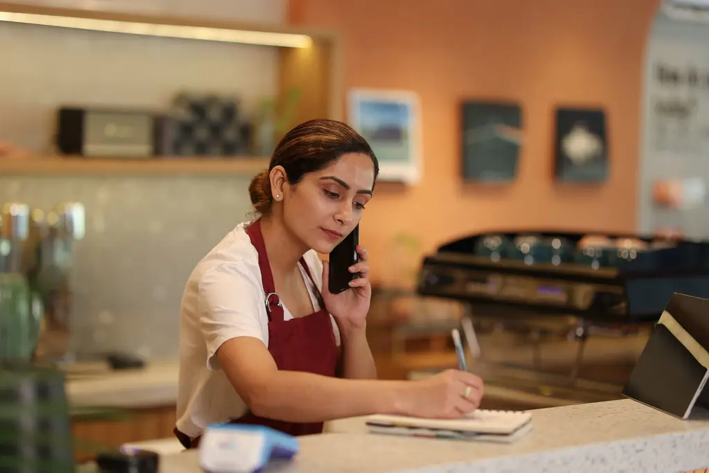 Entrepreneur on the phone at her business counter: outsourced accounting, tax and payroll for small businesses in Peru